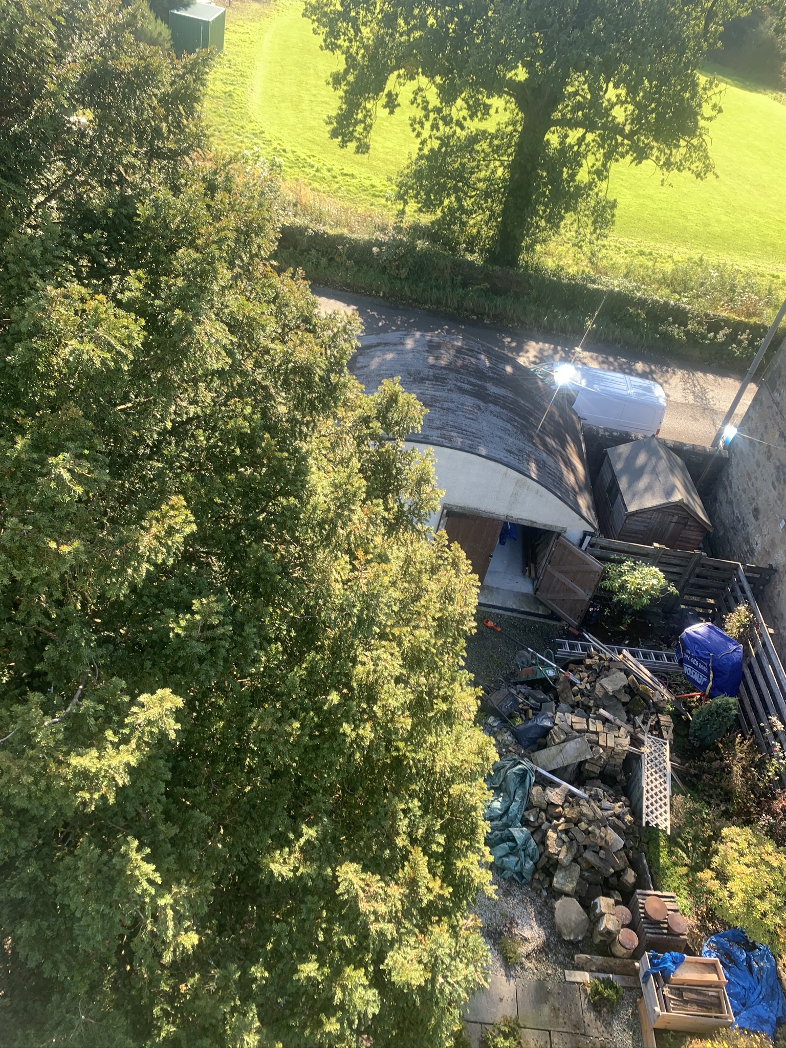 Gallery #1 Aerial view of a garden with mature trees, a shed, and a pile of brick rubble beside a driveway.